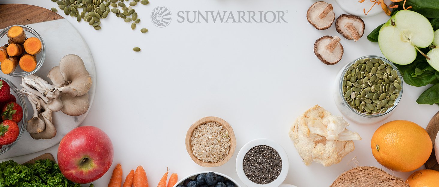 Bird eye view of fruits, vegetables, mushrooms and seeds on white background and the Sunwarrior logo